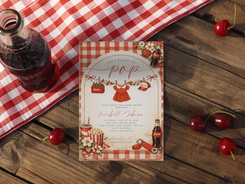 May include: Baby shower invitation with a red and white gingham pattern. The invitation features the text "She's Ready to Pop" and includes a red dress graphic. A bottle of cola, cherries, and popcorn are also visible.