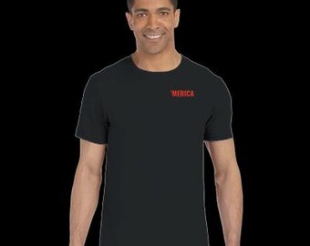 Può includere: T-shirt nero girocollo con la scritta "'MERICA" stampata in rosso sul petto. La maglietta è realizzata in un materiale morbido ed è indossata da una persona. Lo sfondo è nero.