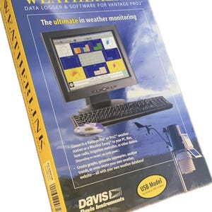 Op de afbeelding: Een blauwe doos voor Weatherlink datalogger en software voor Vantage Pro2. De doos toont een computermonitor met weergegevens, een toetsenbord en een illustratie van een weerstation. De tekst op de doos luidt "The ultimate in weather monitoring."