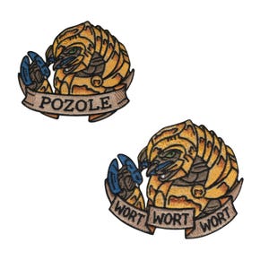 May include: Two embroidered patches featuring a stylized creature with a yellow and brown body, blue claws, and green eyes. One patch has the word "POZOLE" on a banner, the other says "WORT WORT WORT".