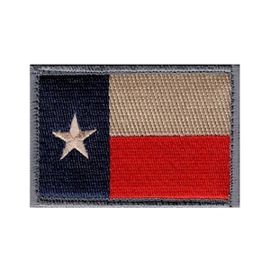 May include: A rectangular embroidered patch featuring the Texas state flag design. The patch has a vertical navy blue stripe on the left with a single white star, and two horizontal stripes on the right in white and red. It has a dark gray border.