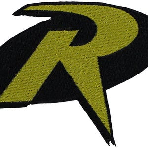 May include: An embroidered patch featuring a stylized letter R in bright yellow thread set against a solid black oval background. The letter has sharp, angular edges and a bold design, with visible stitching texture throughout the entire surface.