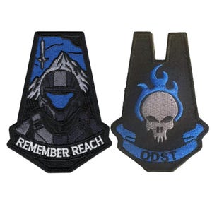 May include: Two black embroidered patches. One features a blue-visored helmet, mountains, and the text "REMEMBER REACH." The other has a skull with blue flames and the text "ODST."