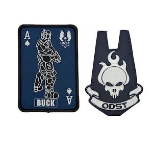 May include: Two embroidered patches. One is a navy blue Ace of Spades playing card with a soldier graphic and the name "BUCK". The other is a navy blue patch with a white skull and the letters "ODST".