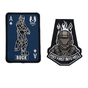 May include: Two embroidered patches. One is a navy blue Ace of Spades card with a soldier graphic and the word "BUCK". The other is a black patch with a soldier graphic and the text "FEET FIRST INTO HELL" and "BUCK".