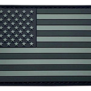 May include: A rectangular morale patch featuring a stylized United States flag design in a monochromatic color scheme. The patch displays a dark field with raised light gray stars and alternating dark and light gray horizontal stripes.