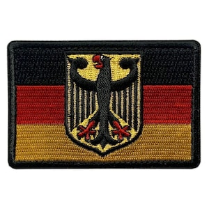 May include: A rectangular embroidered patch featuring the German flag with horizontal black, red, and gold stripes. Centered on the flag is a black eagle emblem with red beak and claws, set against a gold shield background with black vertical lines.