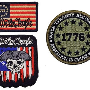 May include: Three embroidered patches featuring patriotic themes. One rectangular patch shows the American flag with 1776 and We the People. A second patch is rectangular with a skull wearing a hat over a flag and We the People. A circular olive patch says When Tyranny Becomes Law Rebellion Is Order 1776.