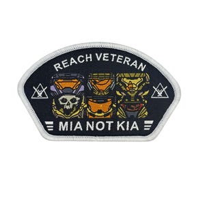 May include: Embroidered patch with a black background and white border. The patch features the text "REACH VETERAN" above three helmet designs and the text "MIA NOT KIA". The helmets are orange, yellow, and purple.
