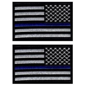 May include: Two rectangular embroidered patches featuring a stylized American flag design. The flag consists of horizontal black and silver-grey stripes with a single horizontal blue stripe, and a field of silver-grey stars on a black background.