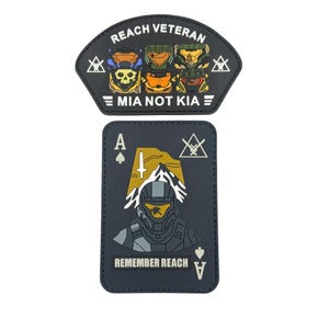May include: Two black patches. The top patch is a fan shape with the text "REACH VETERAN" and "MIA NOT KIA". The bottom patch is rectangular, shaped like an Ace of Spades playing card, with the text "REMEMBER REACH". Both patches feature illustrations of armored figures.