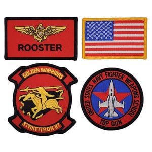 Puede incluir: Un conjunto de cuatro parches bordados que incluye un parche rectangular rojo con alas doradas y el texto ROOSTER, un parche rectangular de la bandera de Estados Unidos, un parche rojo en forma de escudo Golden Warriors Strkfitron 87 y un parche circular Top Gun.