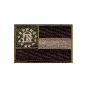May include: A rectangular embroidered patch featuring a muted olive green and dark brown color scheme. The design displays a stylized emblem of the Georgia state flag, with a circle of stars surrounding an arch and pillars on the left side.