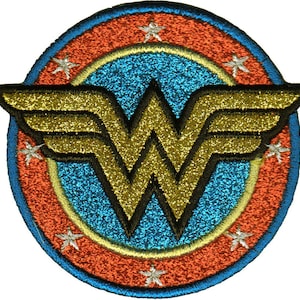 May include: A circular embroidered patch featuring a central gold glitter Wonder Woman logo on a bright blue glitter background. The design is surrounded by an orange glitter border with six small white embroidered stars spaced evenly around it.