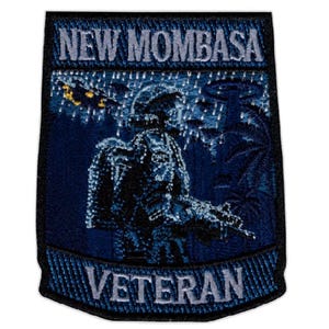 May include: A rectangular embroidered patch with a black border. The top section features the text NEW MOMBASA in light blue. The center depicts a dark blue scene of a soldier in rain with a rifle, and the bottom section reads VETERAN in light blue.