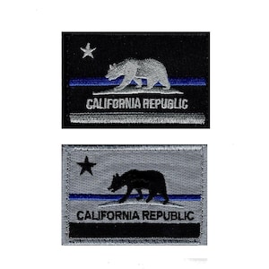 May include: Two rectangular embroidered patches featuring the California Republic flag design. The top patch is black with a white bear, star, and text, and a blue line. The bottom patch is grey with a black bear, star, and text, and a blue line.