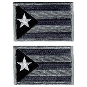 Puede incluir: Dos parches rectangulares bordados con un diseño de bandera en escala de grises. Cada parche muestra una sección triangular negra en el lado izquierdo que contiene una estrella blanca, seguida de franjas horizontales en tonos grises.
