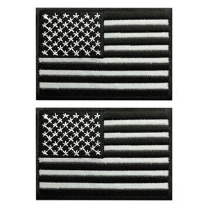 May include: Two rectangular embroidered patches featuring a monochromatic American flag design. Each patch displays a black background with white stitched stars in the canton and horizontal white stripes across the field of the flag.