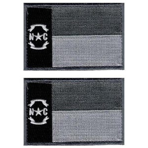 May include: Two rectangular embroidered patches featuring a vertical black stripe on the left side with a white embroidered emblem of the letters N and C flanking a central star. The right side consists of two horizontal stripes in dark and light gray.