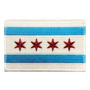 Peut inclure: Un écusson brodé rectangulaire représentant le drapeau de Chicago. L'écusson présente un fond blanc avec deux bandes horizontales bleu clair et quatre étoiles rouges à six branches centrées sur la bande blanche centrale du tissu.