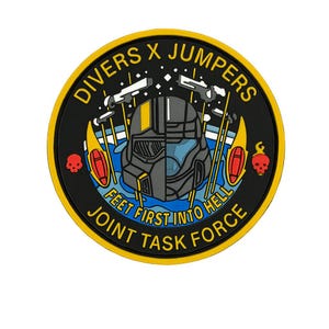 Pode incluir: Um patch circular com fundo preto e borda amarela. O patch apresenta o texto "DIVERS X JUMPERS" e "FEET FIRST INTO HELL JOINT TASK FORCE". O design inclui um capacete dividido, caveiras e equipamentos de mergulho e salto.