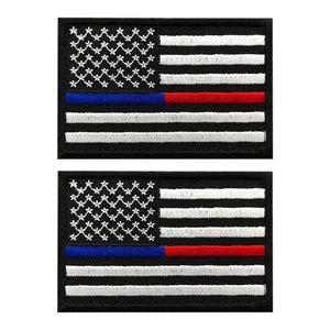 Puede incluir: Dos parches rectangulares bordados con un diseño de bandera estadounidense estilizada. La bandera tiene un fondo negro con símbolos blancos en forma de estrella en el cantón, rayas horizontales blancas y una franja horizontal azul y roja.
