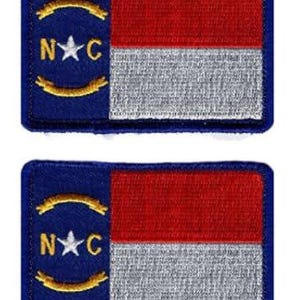 Puede incluir: Dos parches rectangulares bordados con el diseño de la bandera del estado de Carolina del Norte. Cada parche tiene una franja vertical azul a la izquierda con una estrella blanca, las letras N y C en oro y dos pergaminos dorados, seguidos de franjas horizontales rojas y blancas.