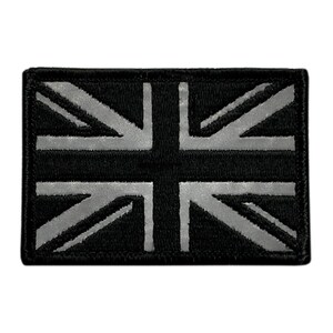 May include: A rectangular embroidered patch featuring a black and grey Union Jack flag design. The patch has a stitched border and displays the iconic British flag pattern in a monochromatic colour scheme with high contrast between the dark and light areas.