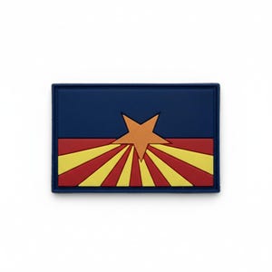 May include: A rectangular patch featuring the Arizona state flag design. The top half is a solid dark blue, while the bottom half displays alternating red and yellow sun rays. A large, centered copper-colored star sits over the rays.