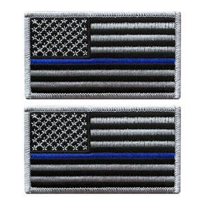 May include: Two rectangular embroidered patches featuring a stylized American flag design. The flag consists of black and grey horizontal stripes with a single horizontal blue stripe, and a black field with white embroidered star patterns.