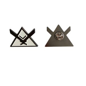 May include: Two triangular enamel pins. One pin is black and white with a geometric design. The other pin is grey with a pin back. Both pins are on a white background.