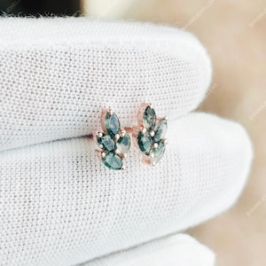 May include: Rose gold stud earrings with a leaf-shaped design, each composed of several green-blue gemstones. The earrings are presented on a white background, highlighting their intricate details and colour.