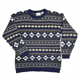 May include: A navy blue sweater with a crew neck and long sleeves. The sweater features a geometric pattern in white, olive green, and brown. The pattern includes diamond and dot designs. The sweater is made of a knit material.