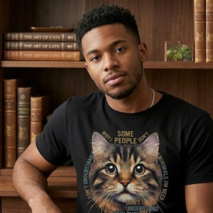 Könnte beinhalten: Schwarzes T-Shirt mit einer detaillierten Katzenillustration. Text um die Katze herum: "Manche Leute verstehen nicht, warum sie Tiere in Not nicht verstehen." Das T-Shirt wird von einer Person getragen.