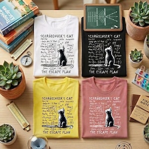 Könnte beinhalten: Vier T-Shirts in Weiß, Schwarz, Gelb und Rosa, jeweils mit dem Text "Schrödinger's Cat", einer Katzenillustration und mathematischen Gleichungen. Der Satz "The Escape Plan" steht darunter. Die Shirts werden mit Sukkulenten und wissenschaftlichen Accessoires präsentiert.