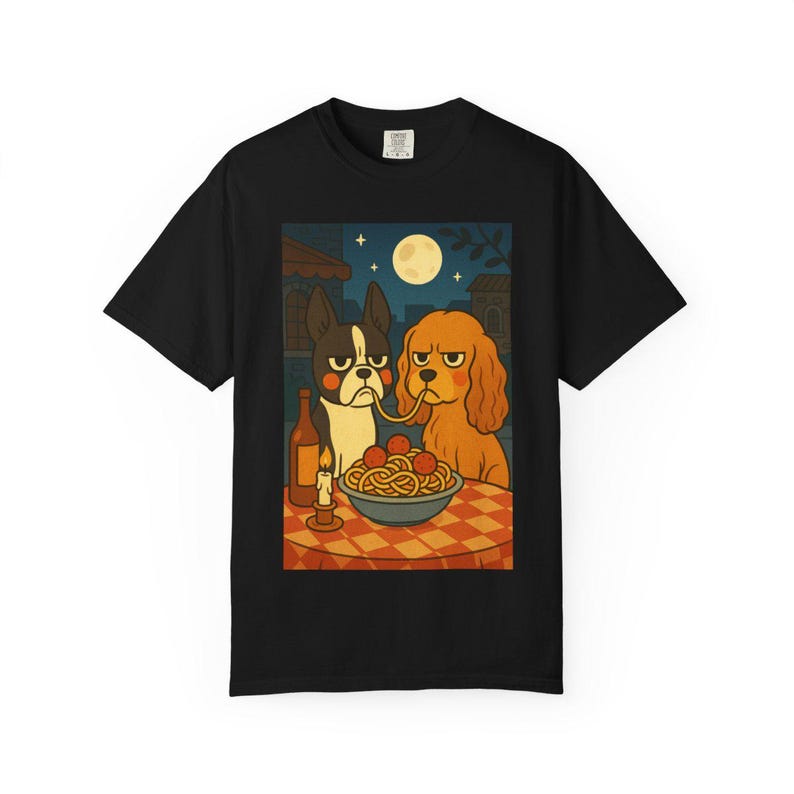 Puede incluir: Camiseta negra con una ilustraci&oacute;n de dos perros compartiendo espaguetis. La escena incluye una botella de vino, una vela encendida y una luna llena en el cielo nocturno. Los perros tienen expresiones de mal humor.