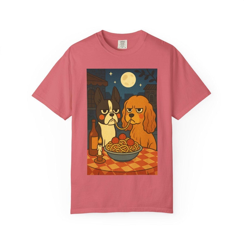 Puede incluir: Camiseta rosa polvoriento con una ilustraci&oacute;n de dos perros compartiendo espaguetis. La escena incluye una botella de vino, una vela encendida y una luna llena en el cielo nocturno. Los perros tienen expresiones gru&ntilde;onas.