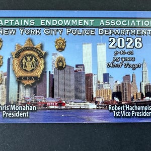 May include: A commemorative card for the New York City Police Department. The card features the text "CAPTAINS ENDOWMENT ASSOCIATION" and "NEW YORK CITY POLICE DEPARTMENT". The card also includes the text "2026", "9-11-01", and "25 years Never Forget". The card has a cityscape background.