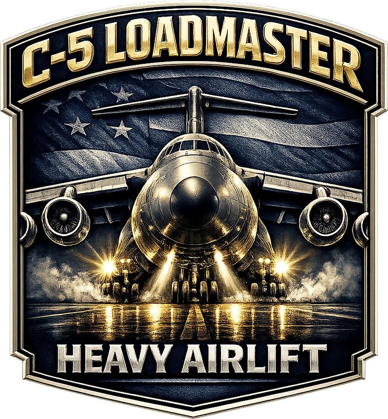 May include: A shield-shaped emblem featuring a C-5 Galaxy aircraft centered on a runway with bright landing lights. The text C-5 LOADMASTER appears in gold at the top, and HEAVY AIRLIFT is in silver at the bottom, set against a dark American flag.