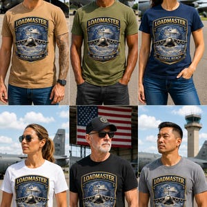 Puede incluir: Una camiseta de manga corta y cuello redondo con un estampado gr&aacute;fico de un avi&oacute;n de transporte militar centrado en un emblema de escudo. El texto LOADMASTER aparece arqueado sobre el avi&oacute;n, con GLOBAL REACH impreso en la parte inferior.