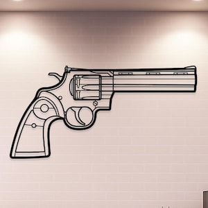 Pode incluir: Uma peça de arte de parede em metal preto em forma de revólver. A arma é retratada em um estilo minimalista, com linhas limpas e foco na silhueta da arma. A obra de arte é montada em uma parede de tijolos brancos.