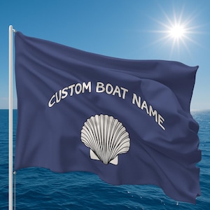 Puede incluir: Una bandera de barco azul marino con el texto blanco "CUSTOM BOAT NAME" y un diseño de concha blanca. La bandera ondea al viento sobre un fondo de cielo azul y océano.