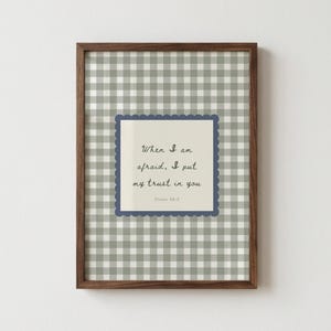 May include: A framed print with a brown wooden frame. The print features a gray and white gingham pattern background. A square with a scalloped edge and a blue border contains the text "When I am afraid, I put my trust in you" and "Psalm 56:3".
