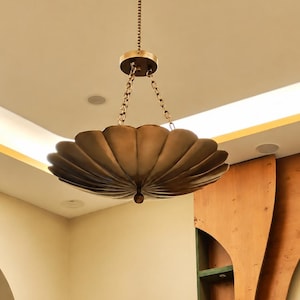 May include: A hanging pendant light fixture featuring a wide, scalloped, bowl-shaped shade in a metallic bronze finish. The shade is suspended from the ceiling by a central chain and three smaller chains connected to a circular mounting canopy.