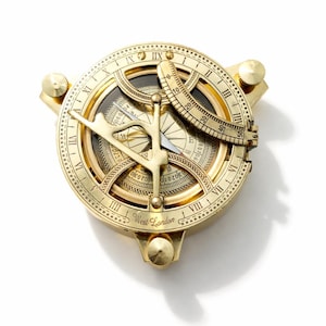 Puede incluir: Un compás de reloj de sol circular de latón con números romanos, una escala curva ajustable y un gnomon central. La base está grabada con el texto West London. Incluye tres pequeños pies niveladores y marcas internas detalladas.