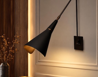 May include: A wall-mounted swing arm lamp featuring a matte black conical shade with a gold interior finish. The fixture has a slender, adjustable dark metal arm attached to a square wall plate, providing directional lighting for interior spaces.
