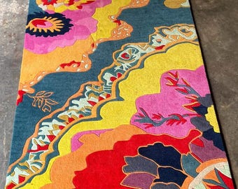 May include: A rectangular area rug featuring a vibrant, abstract floral pattern with bold blocks of teal, bright yellow, hot pink, orange, and deep red. The design includes flowing, organic shapes and intricate, multi-colored decorative borders.