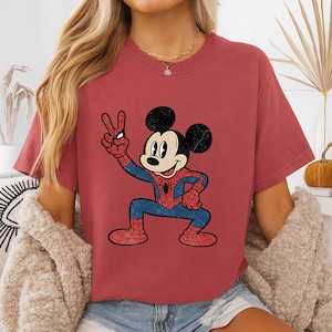 A woman wearing a red t-shirt with a cartoon character of Mickey Mouse and Spider-Man printed on it.