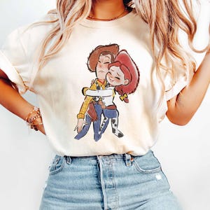 A woman wearing a white t-shirt with a cartoon character printed on it, paired with blue jeans.