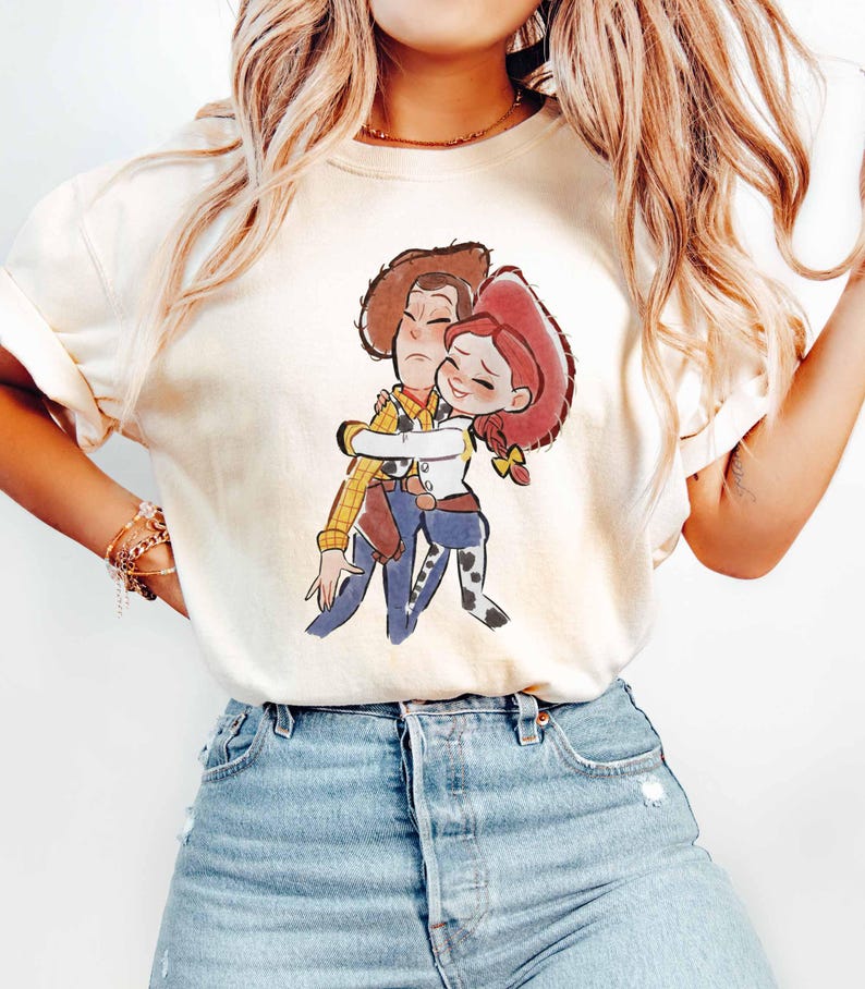A woman wearing a white t-shirt with a cartoon character printed on it, paired with blue jeans.